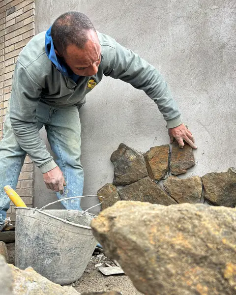 Maestro de obra instalando piedra natural en fachada