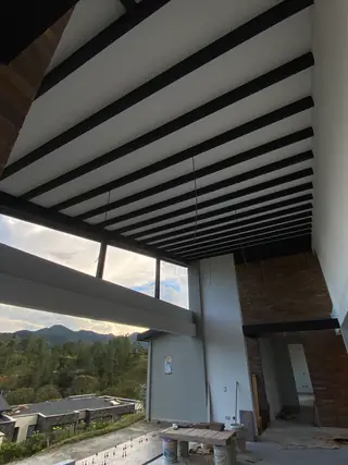 Espacio a doble altura con vigas a la vista y ventanal hacia las montañas