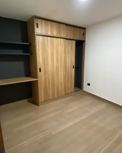 Habitación con mueble de estudio y closet en madera