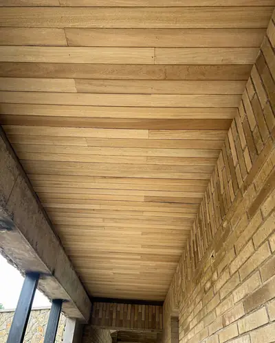 Corredor con cielo raso en madera y muro en ladrillo a la vista