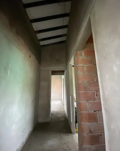 Corredor en obra gris con muros en ladrillo