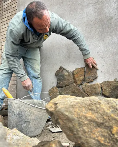 Maestro de obra instalando piedra natural en fachada