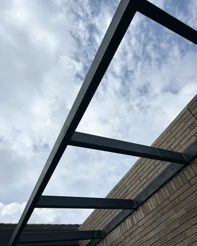 Pérgola metálica junto a muro en ladrillo