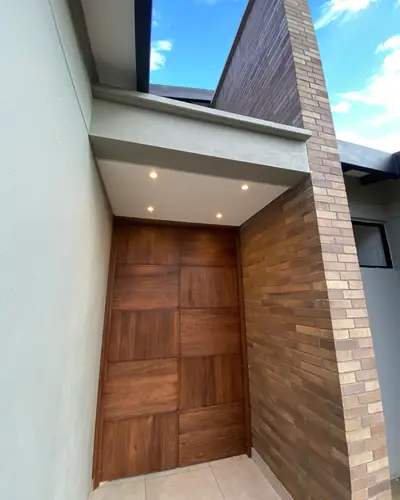 Acceso principal con puerta en madera y enchape en ladrillo