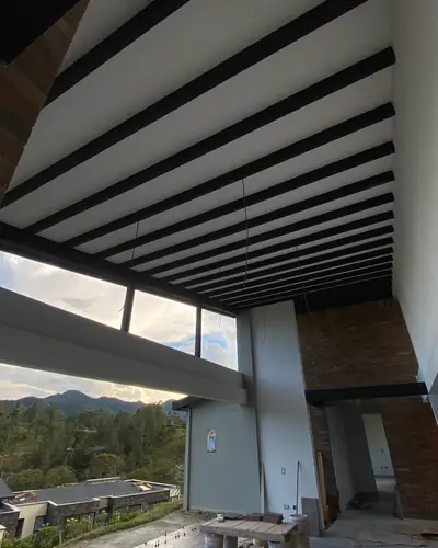 Espacio a doble altura con vigas a la vista y ventanal hacia las montañas