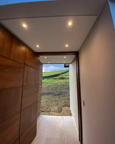 Acceso cubierto con puerta en madera e iluminación empotrada