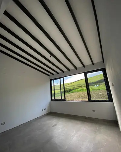 Habitación con vigas en el techo y ventana hacia el campo