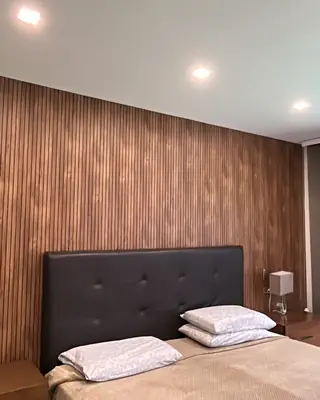 Habitación terminada con muro en listones de madera e iluminación empotrada