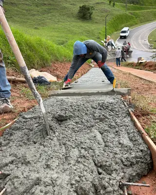 Trabajador extendiendo concreto en una placa huella con malla de refuerzo